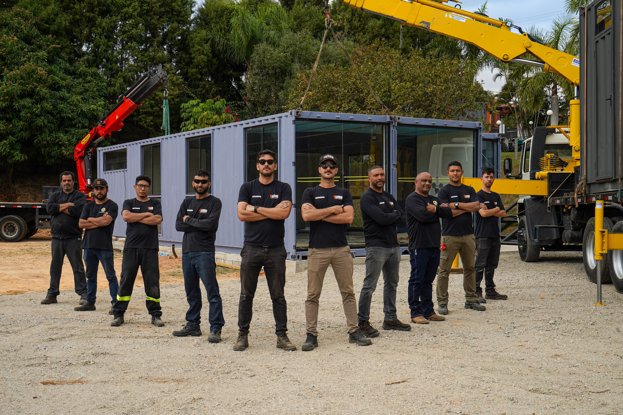 Equipe Verini Containers em frente a um módulo entregue, com guindastes de içamento ao fundo